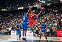 Jogo de basquetebol em pavilhão desportivo com equipas em acção durante partida de qualificação