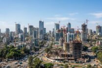 Edifícios modernos e gruas de construção simbolizando desenvolvimento económico numa cidade africana